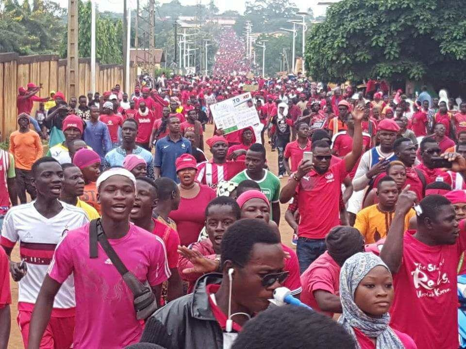 African protesters marching in large numbers, symbolizing public dissent against political issues such as term limit reforms